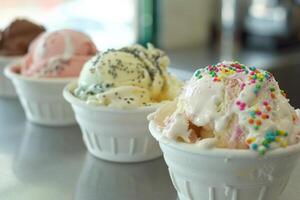 Ice cream scoops with sprinkles sitting in bowls on metal counter photo