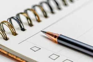 Pen lying on spiral notebook with checkboxes, ready for writing photo