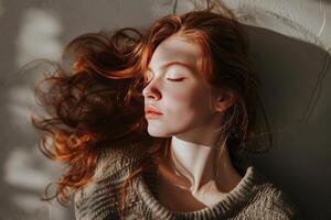Redhead model resting on floor with eyes closed, enjoying sunlight photo