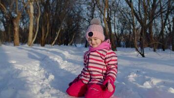 Joyful little child girl running towards on snowy road, looking at camera in winter park forest video
