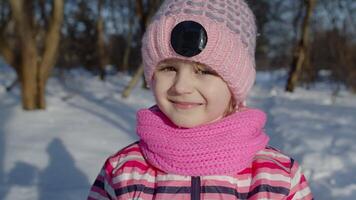 Joyful little child girl looking at camera, smiling, fooling around, making faces in winter park video