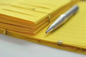 Silver pen lying on yellow notepad with stack of folded papers photo