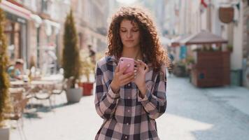 Young woman use smartphone typing text messages browsing internet finishing work looking at camera video
