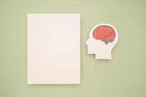 A blank white paper and a red brain shape symbol on a green background. Space for text. photo
