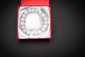 Close-up of a white jade bangle or bracelet in a red box on a black background. photo