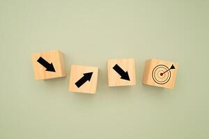 Wooden cubes with black arrows pointing to the dartboard icon on a green background photo