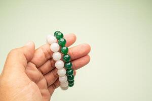 Close-up of a jade bangles or bracelets in hand against a green background. Space for text. photo