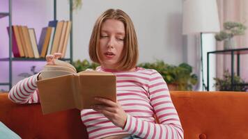 Young woman relaxing interesting book turning pages smiling enjoying literature taking rest on sofa video