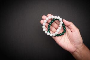 Jade bangles or bracelets in hand against a black background. Space for text. photo