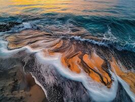 Waves gently rolling onto a sandy beach at sunset, creating a serene and tranquil atmosphere with vibrant colors reflected in the water. photo
