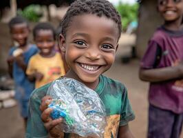 A joyful child smiles while holding a plastic bottle, surrounded by friends in a lively outdoor setting. photo