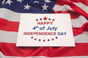 The text of Happy 4th of July Independence day on a white paper over the American flag background photo