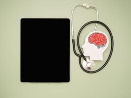 A brain shape symbol, a stethoscope, and a tablet on a green background photo