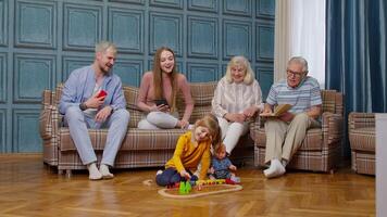 Happy multigenerational family leisure at home couple parents and grandpagents relaxing on sofa video
