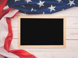 Part of the American flag and a mini chalkboard on a wooden table. Copy space with text. photo