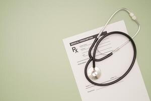 Top view of a stethoscope over the medical prescription sheet on a green background. Space for text. photo