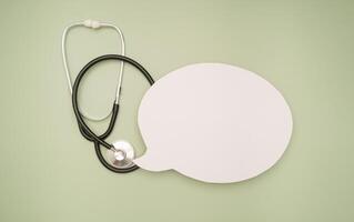 Top view of a stethoscope and a blank white speech bubble on a green background. Space for text. photo