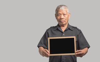 Portrait of Asian man holding a mini blackboard and looking at the camera with a smile while standing on a gray background. Space for text. photo
