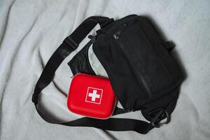A vivid bright red box featuring a striking cross symbol is carefully placed next to a sturdy black bag, resulting in a captivating and interesting visual contrast between the two items photo