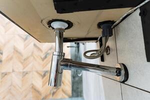 This is a bathroom sink that features a drain pipe which is hanging from it, as commonly found in many homes, showcasing typical plumbing fixtures and household hardware elements photo