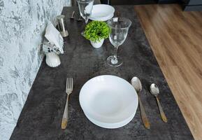 There is a beautifully arranged table featuring plates, silverware, glasses, and a lovely plant placed on it, creating an inviting and warm atmosphere for dining or serving meals photo
