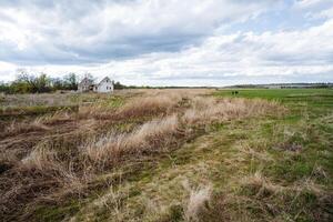 imagen un sereno campo paisaje ese caracteristicas un abandonado casa graciosamente anidado en medio de un asombroso monitor de lozano verdor, junto a distante campos ese tramo hacia el horizonte foto