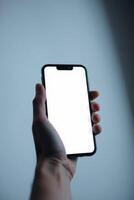 Person holding modern smartphone with blank white screen up close view photo