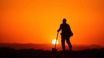 Silhouette of construction worker with shovel against a vibrant sunset sky photo