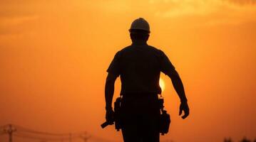 Silhouette of construction worker against a vibrant su photo