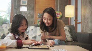 Asian family, mum, and kid fun playing checkers board game-GO on table in home living room together with love and cheerful, happy weekend relaxing hobby of child and parent, concentrate and compete. photo