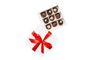 Delicious chocolate pralines red box for Valentine's Day. Heart shaped box of chocolates top view isolated on white background photo