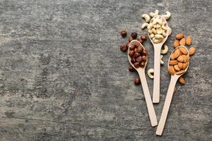 Assortment nuts wooden spoon on colored table. Cashew, hazelnuts, walnuts, almonds. Mix of nuts Top view with copy space photo