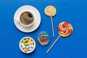 Coffee cup with chocolates colored candy. Top view on table background with copy space photo