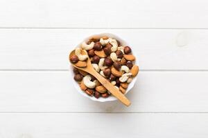 Assortment of nuts wooden bowl on colored table. Cashew, hazelnuts, walnuts, almonds. Mix of nuts Top view with copy space photo