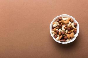 Assortment nuts in wooden bowl on colored table. Cashew, hazelnuts, walnuts, almonds. Mix nuts Top view with copy space photo