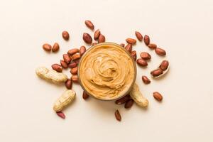 Bowl of peanut butter and peanuts table background. top view with copy space. Creamy peanut pasta small bowl photo