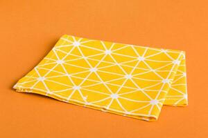 top view with yellow empty kitchen napkin isolated on table background. Folded cloth for mockup with copy space, photo