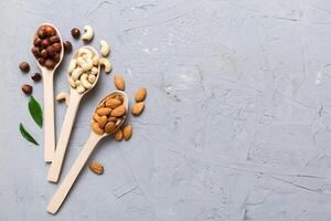 Assortment of nuts wooden spoon on colored table. Cashew, hazelnuts, walnuts, almonds. Mix of nuts Top view with copy space photo
