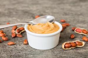 Bowl of peanut butter and peanuts table background. top view with copy space. Creamy peanut pasta photo