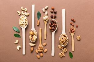mixed nuts white wooden spoon. Mix of various nuts on colored background. pistachios, cashews, walnuts, hazelnuts, peanuts and brazil nuts photo