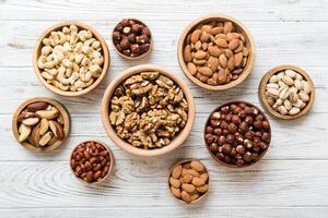 mixed nuts wooden bowl. Mix of various nuts on colored background. pistachios, cashews, walnuts, hazelnuts, peanuts and brazil nuts photo