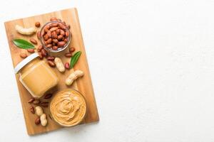 Bowl peanut butter and peanuts on table background. top view with copy space. Creamy peanut pasta in small bowl photo