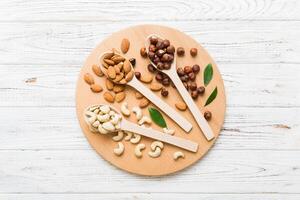 Assortment nuts in wooden spoon on colored table. Cashew, hazelnuts, walnuts, almonds. Mix of nuts Top view with copy space photo