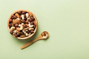 Assortment nuts in wooden bowl on colored table. Cashew, hazelnuts, walnuts, almonds. Mix of nuts Top view with copy space photo