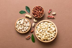 mixed nuts in wooden bowl. Mix various nuts on colored background. pistachios, cashews, walnuts, hazelnuts, peanuts and brazil nuts photo