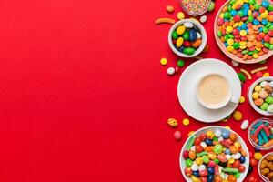 Coffee cup chocolates and colored candy. Top view on table background with copy space photo