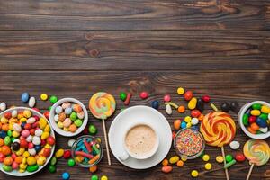 Coffee cup with chocolates and colored candy. Top view table background copy space photo
