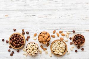 Assortment nuts wooden bowl on colored table. Cashew, hazelnuts, walnuts, almonds. Mix of nuts Top view with copy space photo
