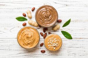 Glass jar with peanut butter table background, top view space text and close up photo