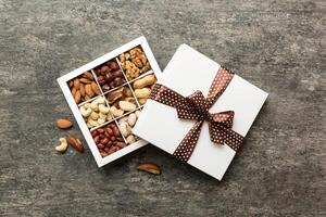 Various varieties of nuts lying in paper box on table background. Top view. Healthy food. Close up, copy space, top view, flat lay. Walnut, pistachios, almonds, hazelnuts and cashews photo